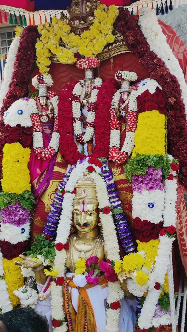Temple deities decorated with colourful flower garlands during a celebration