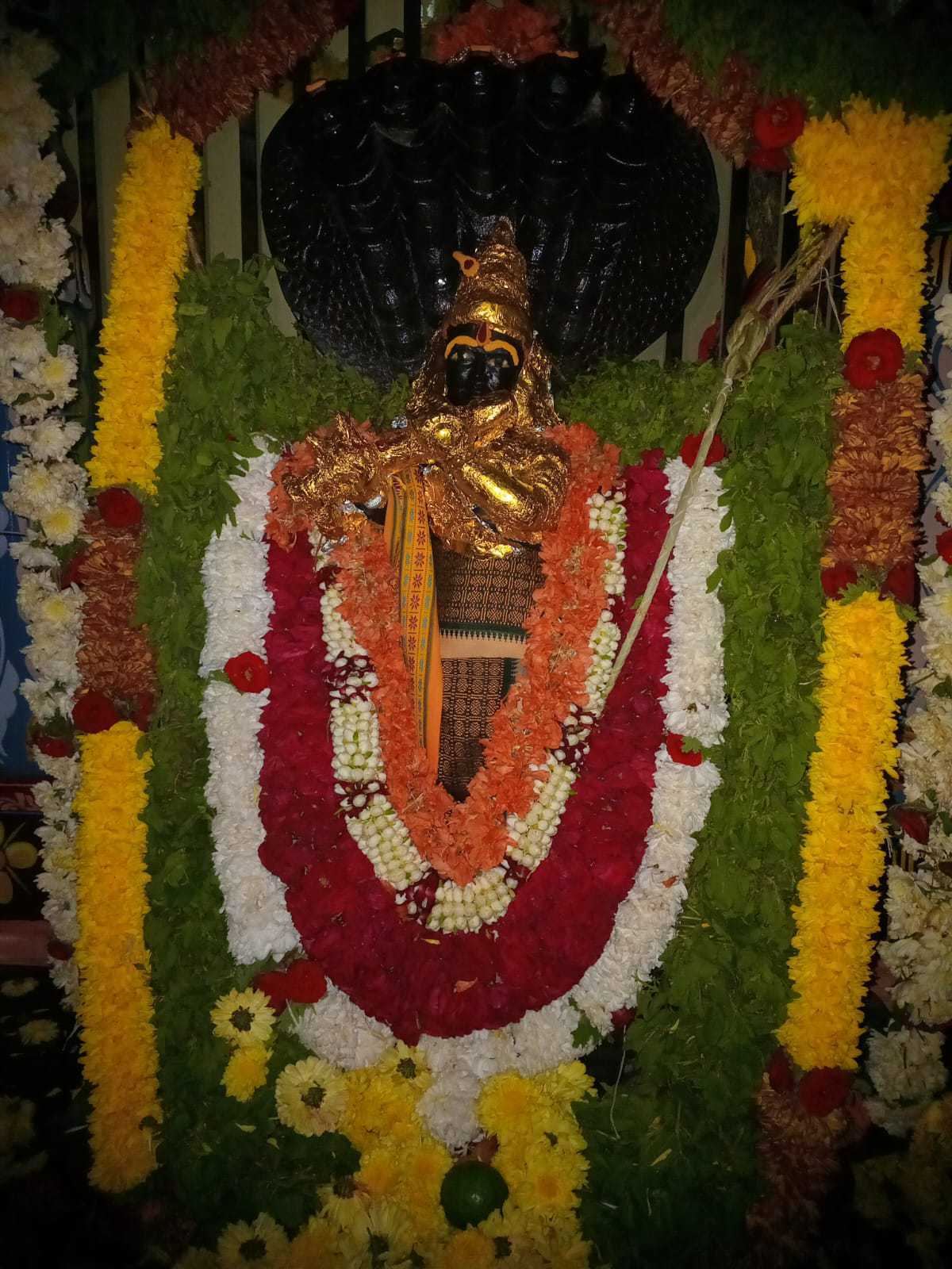 Temple deity adorned with layered flower garlands